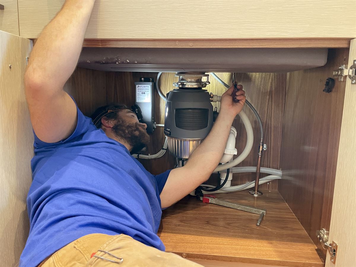 Technician installing under-sink plumbing