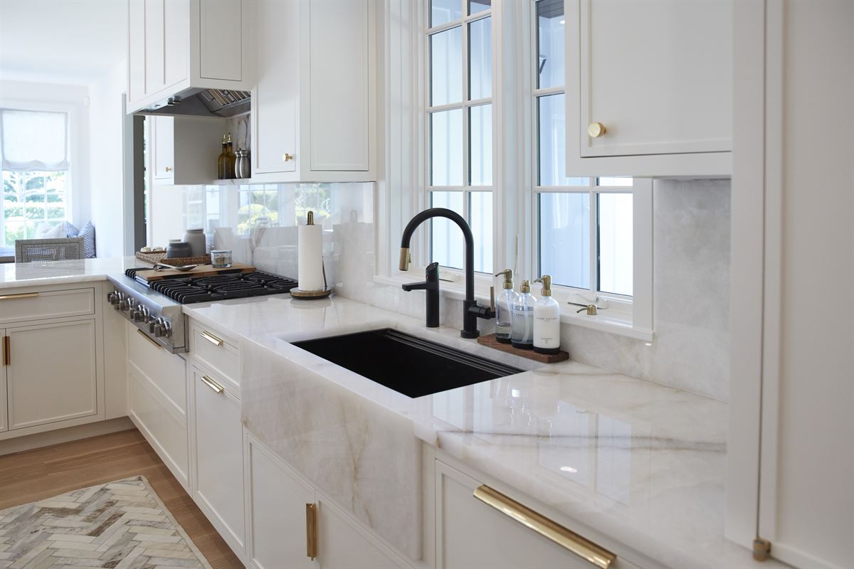 Luxury kitchen with marble counters, black farmhouse sink and brass hardware