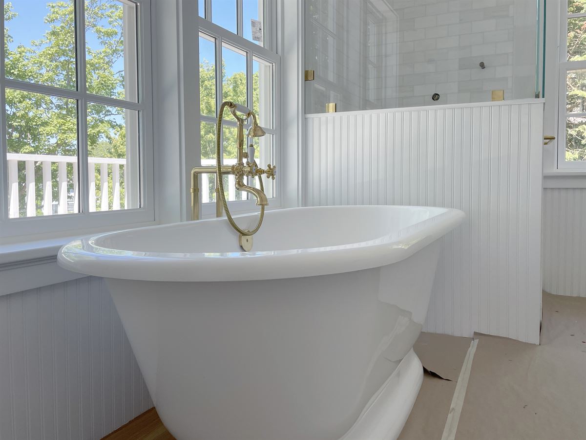 Freestanding clawfoot tub with brass floor-mount fixtures in a sunlit bathroom